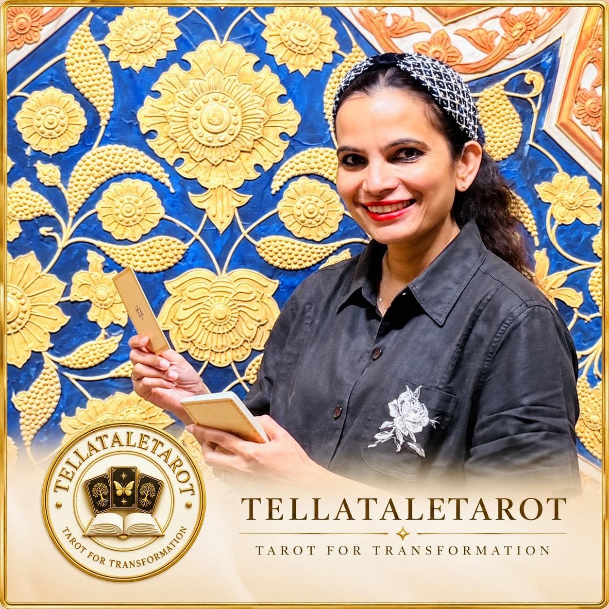 Chandra aka TELLATALETAROT holding Tarot cards in front of a gold floral wall, with the TELLATALETAROT logo
